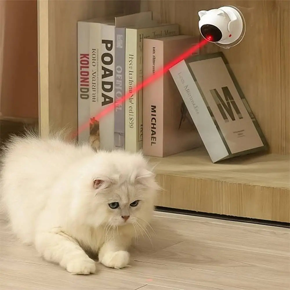 Jouet interactif blanc avec faisceau rouge, chat blanc à proximité sur le sol.