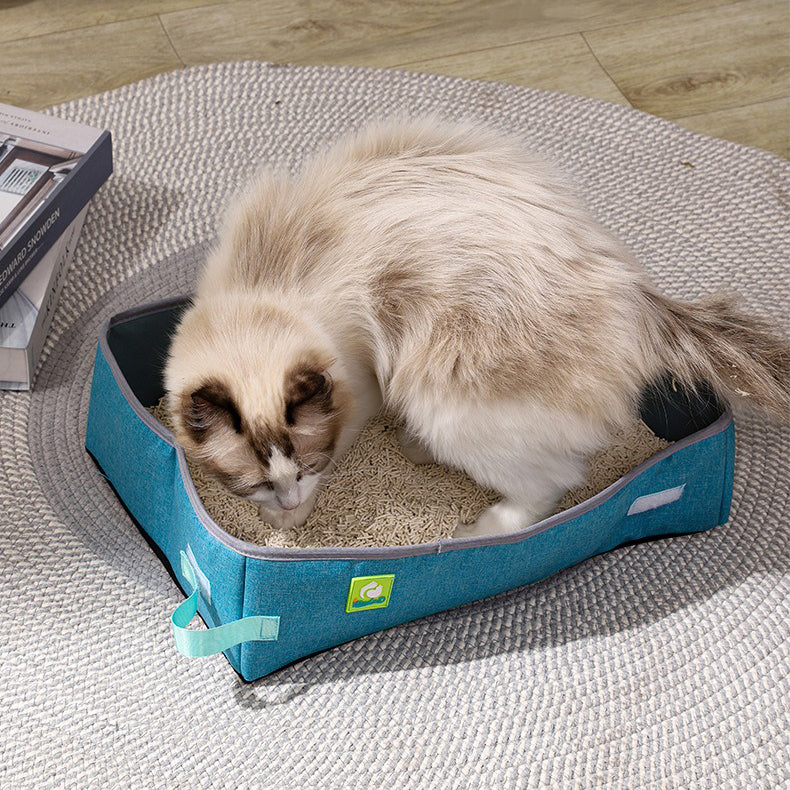 Bac à litière pliable bleu pour chat, chat blanc et beige dans la litière.