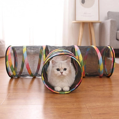 Tunnel pliable pour chat en tissu noir gris, entrée circulaire et chat blanc à l’intérieur.