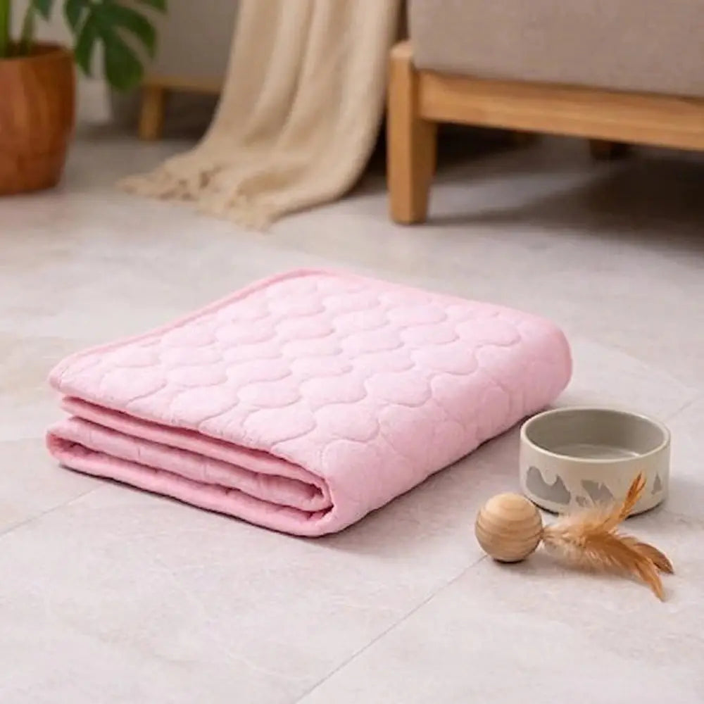 Tapis rafraîchissant pour chat rose clair, plié en deux, surface matelassée texturée.
