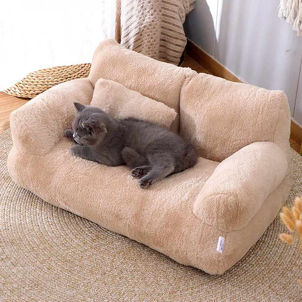 Panier pour chat en peluche beige, coussin central et rebords ronds, chat gris couché.