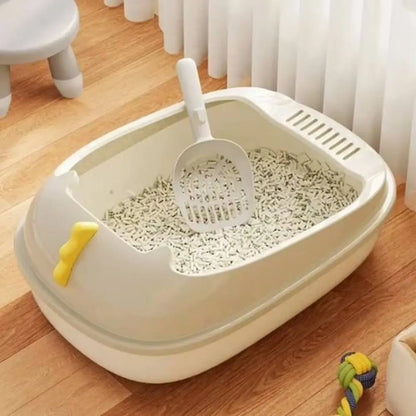 Bac à litière pour chat beige/blanc, intérieur avec grille et litière, pelle jaune visible.
