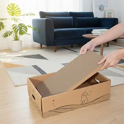 Griffoir pour chat en carton beige, rabat ouvert, mains tenant le dessus de la boîte.