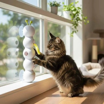 Jouet interactif pour chat blanc aux antennes vertes, chat tigré près d’une baie vitrée
