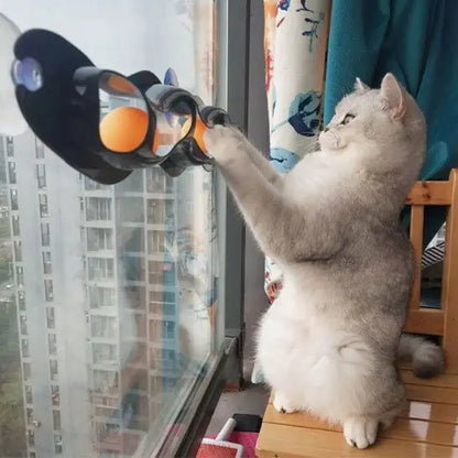 Jouet interactif pour chat à ventouses, barre noire ondulée avec éléments orange et bleus, chat blanc