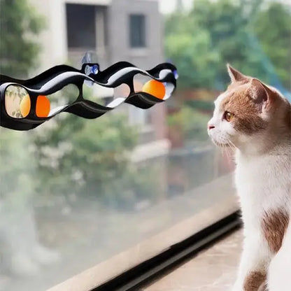 Jouet interactif pour chat à ventouses, barre noire ondulée avec détails orange et bleus, chat roux