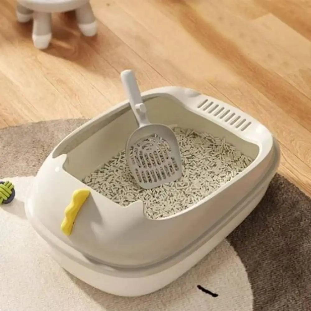 Bac à litière pour chat beige/blanc avec pelle et grille, bac intérieur rempli de litière.