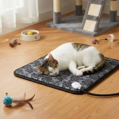 Tapis chauffant pour chat gris foncé à motif, bord noir, interrupteur blanc visible.