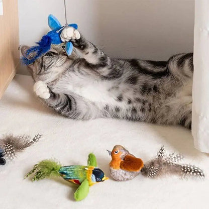 Jouet pour chat oiseaux en peluche : bleu suspendu, vert et marron au sol.