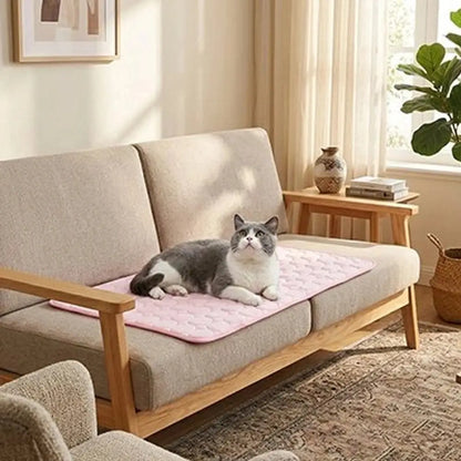Tapis rafraîchissant pour chat rose clair, posé sur un canapé, chat couché dessus.