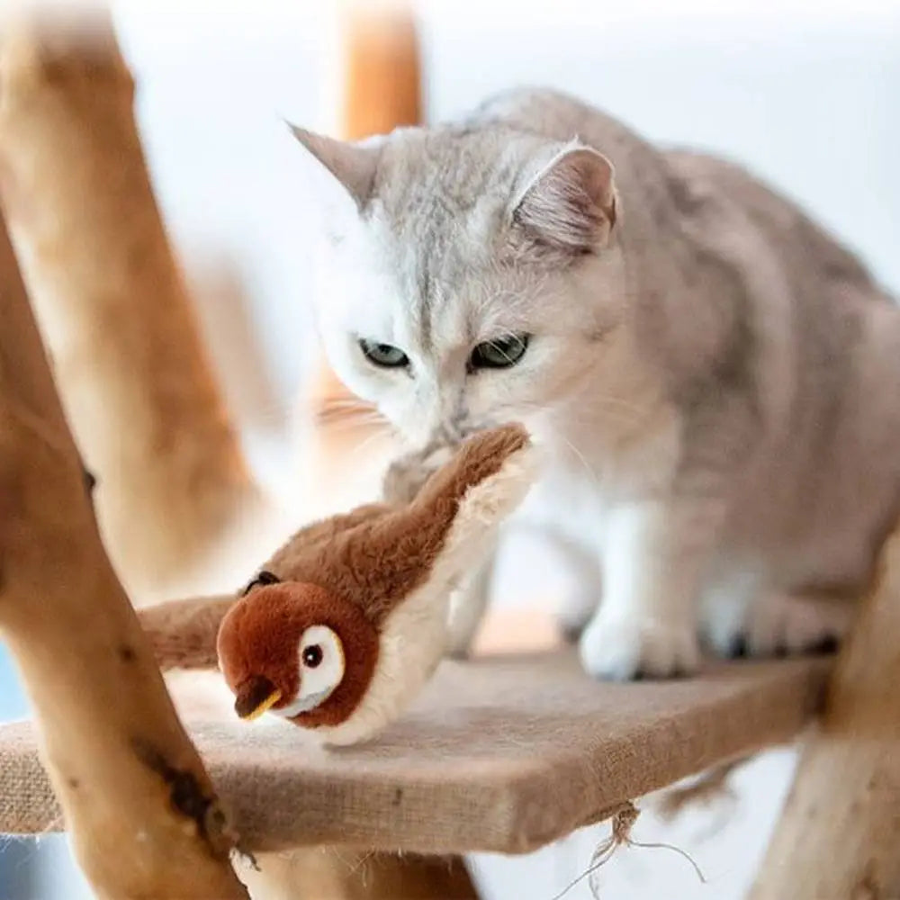 Jouet oiseau en peluche brun avec yeux ronds, posé au bord d’un support