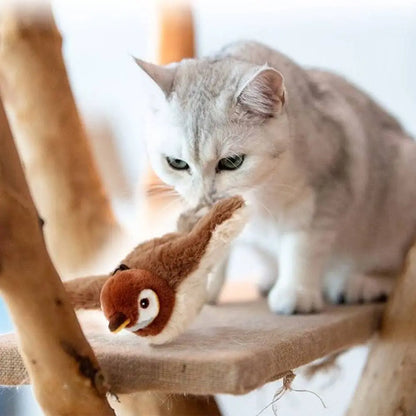 Jouet oiseau en peluche brun avec yeux ronds, posé au bord d’un support