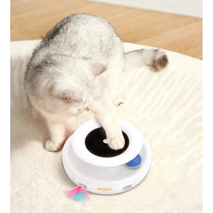 Jouet interactif pour chat : socle blanc avec bouton noir et plume multicolore.