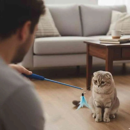 Canne à pêche pour chat, poignée bleue et plume bleue pendante près du chat