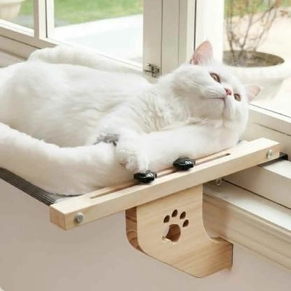 Hamac pour chat de fenêtre avec coussin blanc, cadre bois, chat blanc étendu.