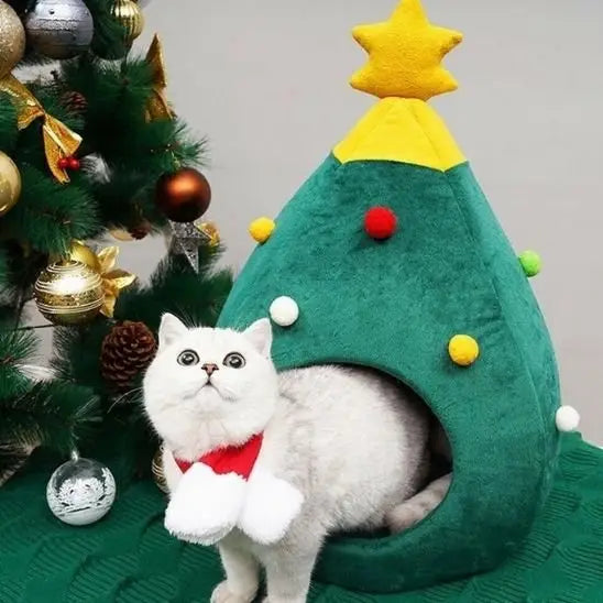Maison pour chat sapin verte en tissu, ouverture ronde, chat blanc debout avec nœud rouge.