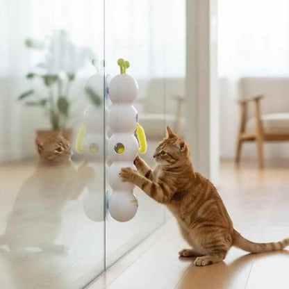 Jouet interactif pour chat blanc à antennes vertes, chat tigré joue près d’une vitre